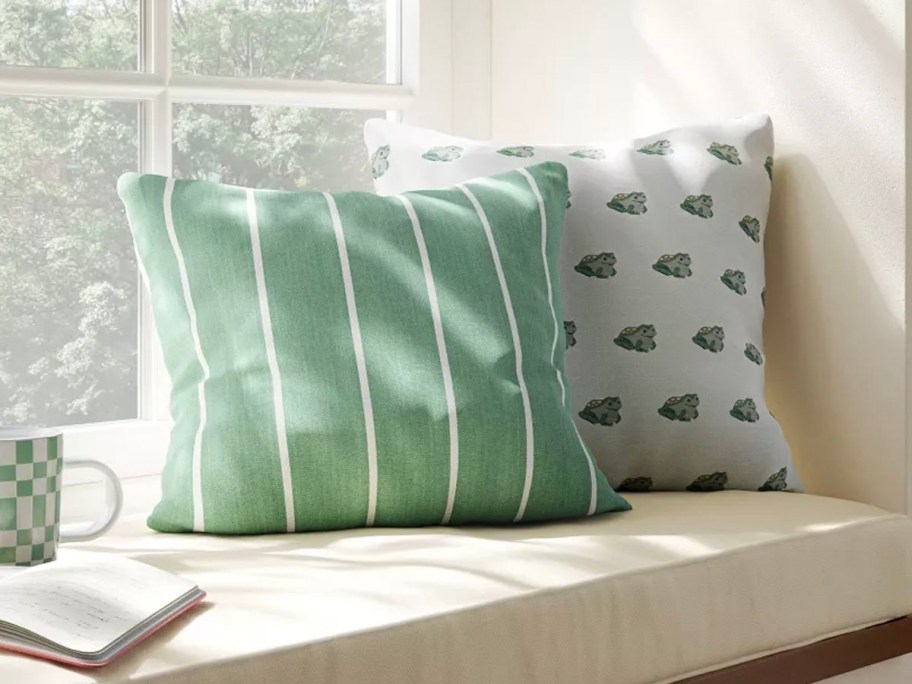 green and frog throw pillows sitting on windowsill