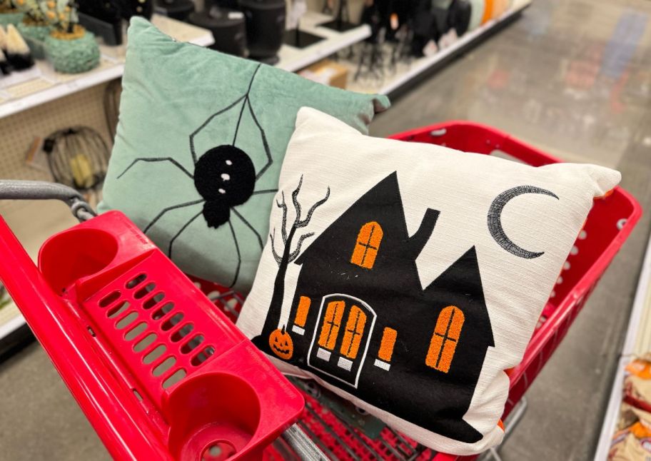 spider and haunted house halloween throw pillows arranged in a red target shopping cart