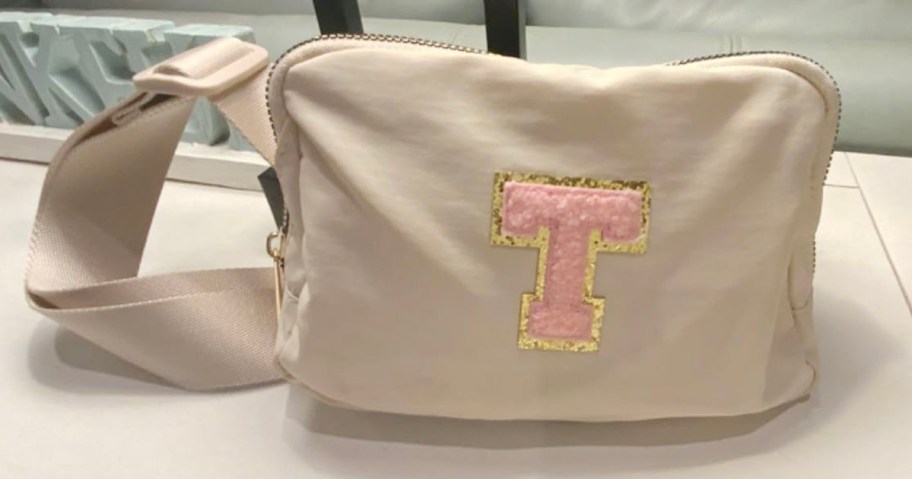 beige t initial belt bag on table