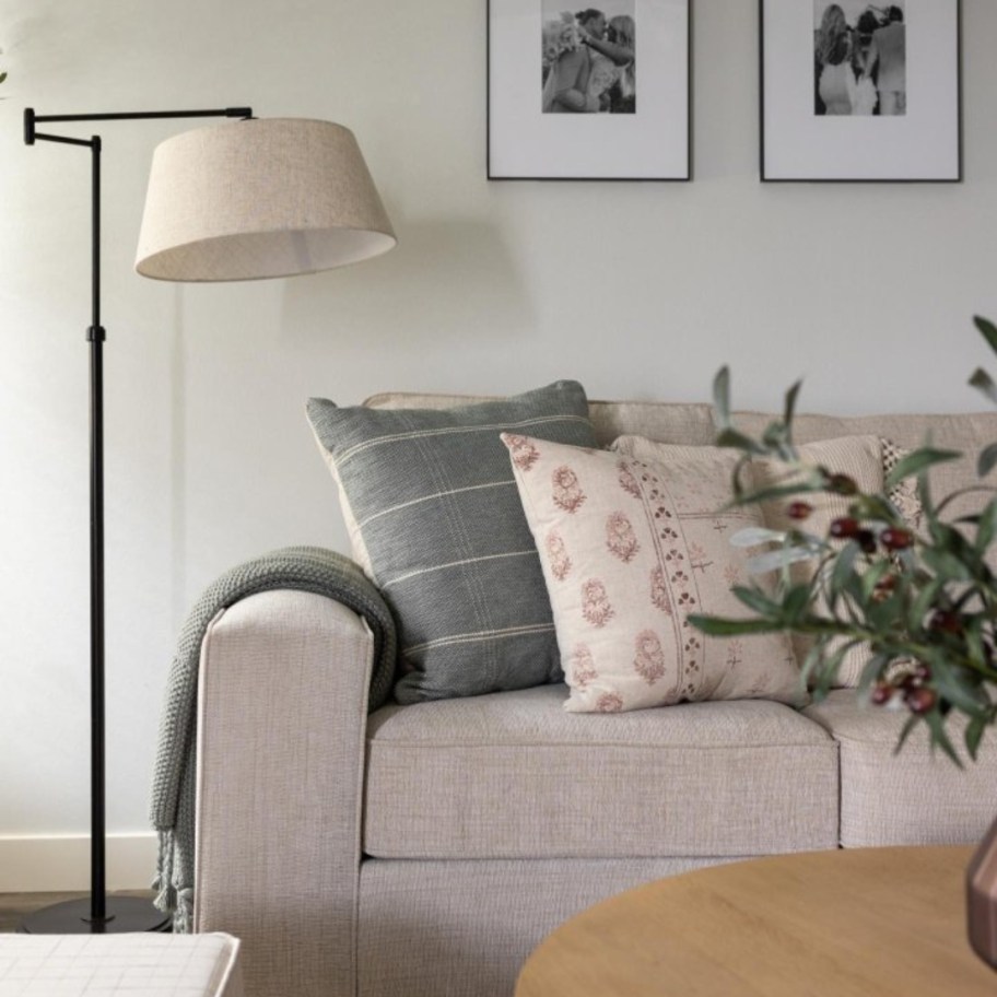 adjustable floor lamp with black base and arm and tan shade in a living room