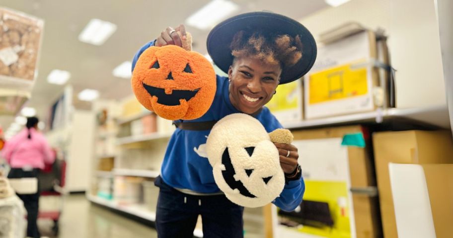 woman holding pumpkin pillows in store