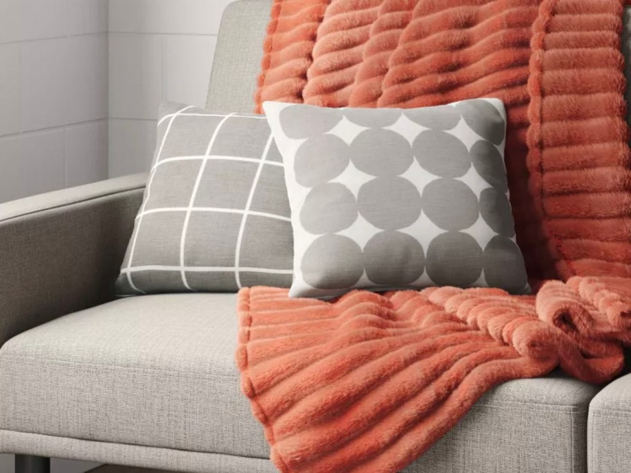 two gray throw pillows on couch with orange blanket 