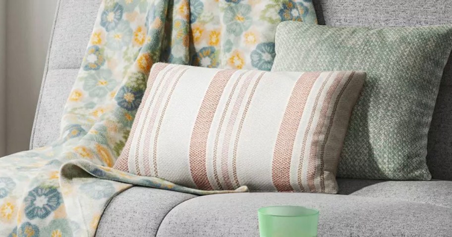 white and pink striped throw pillow with green pillow and blanket on couch