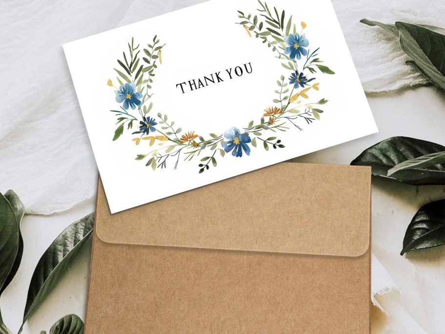 thank you card and envelope on table with leaves