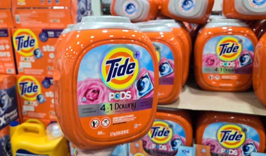 A container of Tide detergent pods is stacked on a pallet in a Costco warehouse.