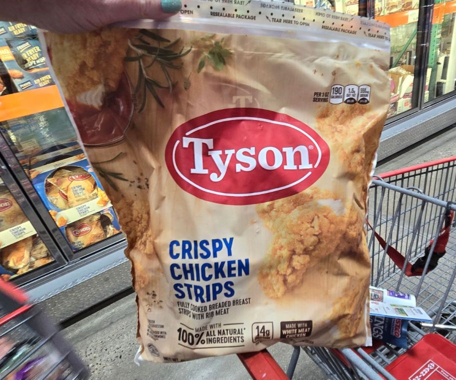 a woman's hand holding a bag for tyson frozen chicken strips