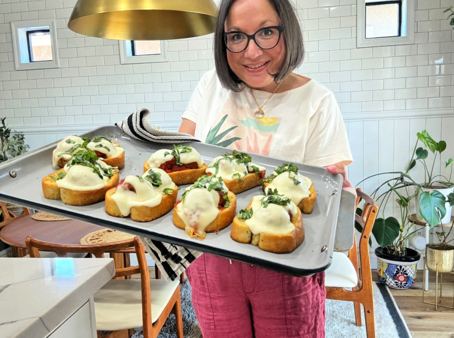 woman holding sheet pan with texas toast and meatballs