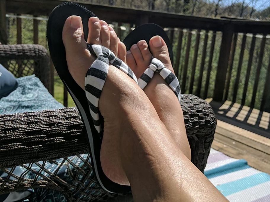 a womans feet wearing a pair of striped flip flops