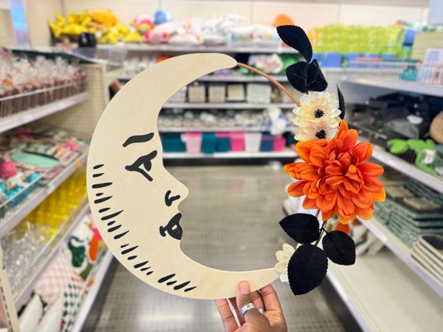 womans hand holding a quarter moon wreath