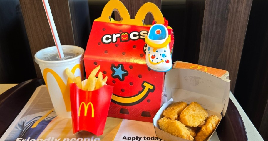 a McDonald's Crocs Happy Meal container with the toy Croc shoe, drink, fries and nuggets on tray around it