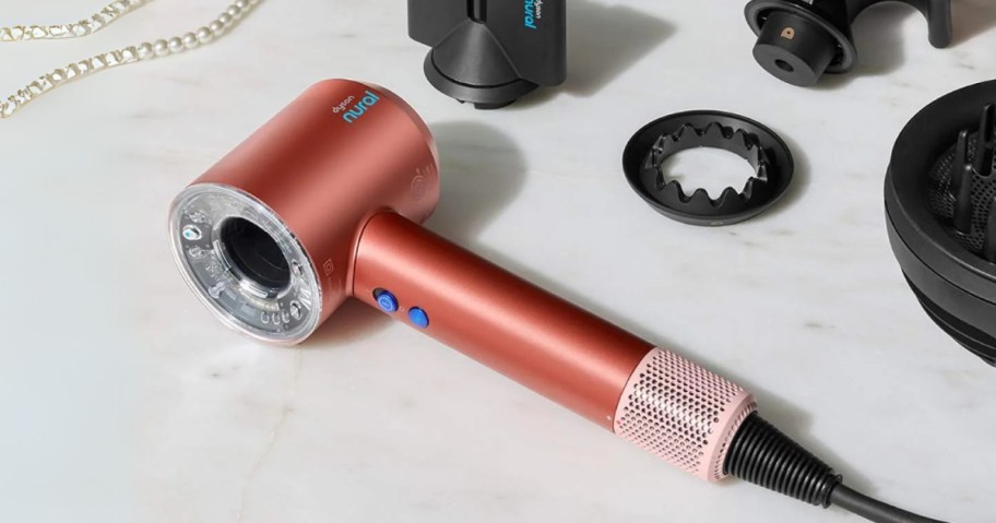 a pink Dyson Supersonic Nural Hair Dryer with Accessories