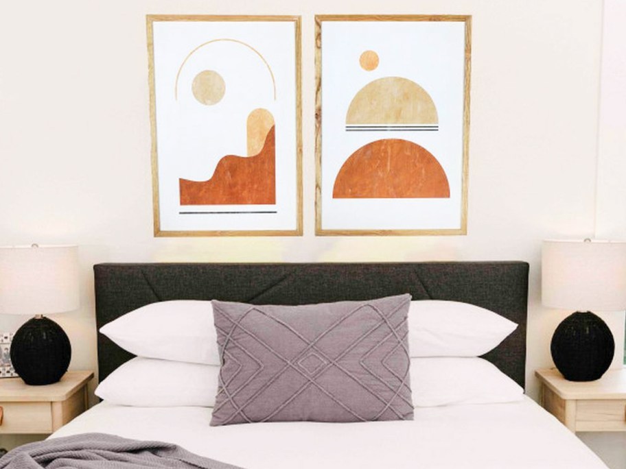 two art prints hanging over bed