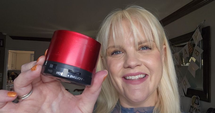 woman holding red bluetooth speaker