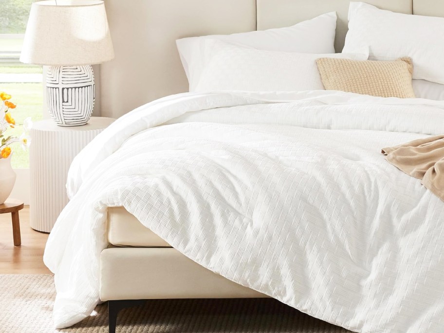 white onlineforter with matching pillow shams and white sheets on a bed