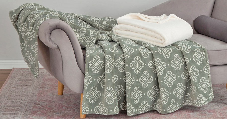 green and white throw draped over couch with folded white throw on top