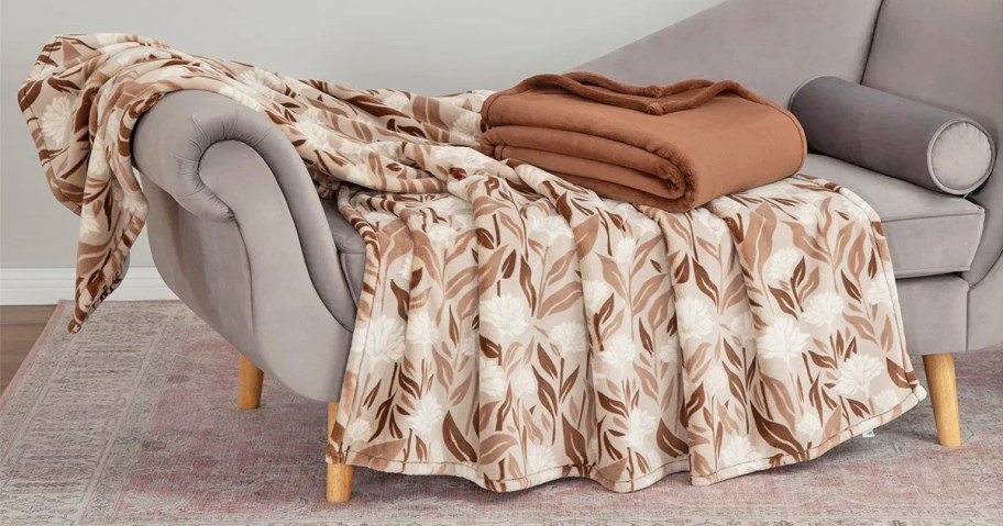 brown and white throw draped over couch with folded brown throw on top