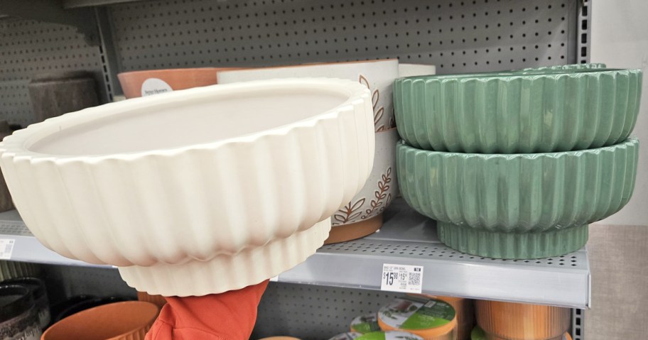 hand holding up white planter in front of matching green ones