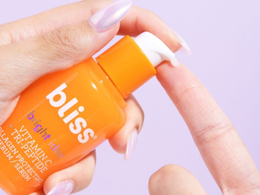 Hand pumping a bottle of Bliss Vitamin C Serum on an index finger