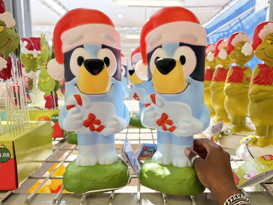 hand touching two Bluey Christmas Blow Molds on store shelf