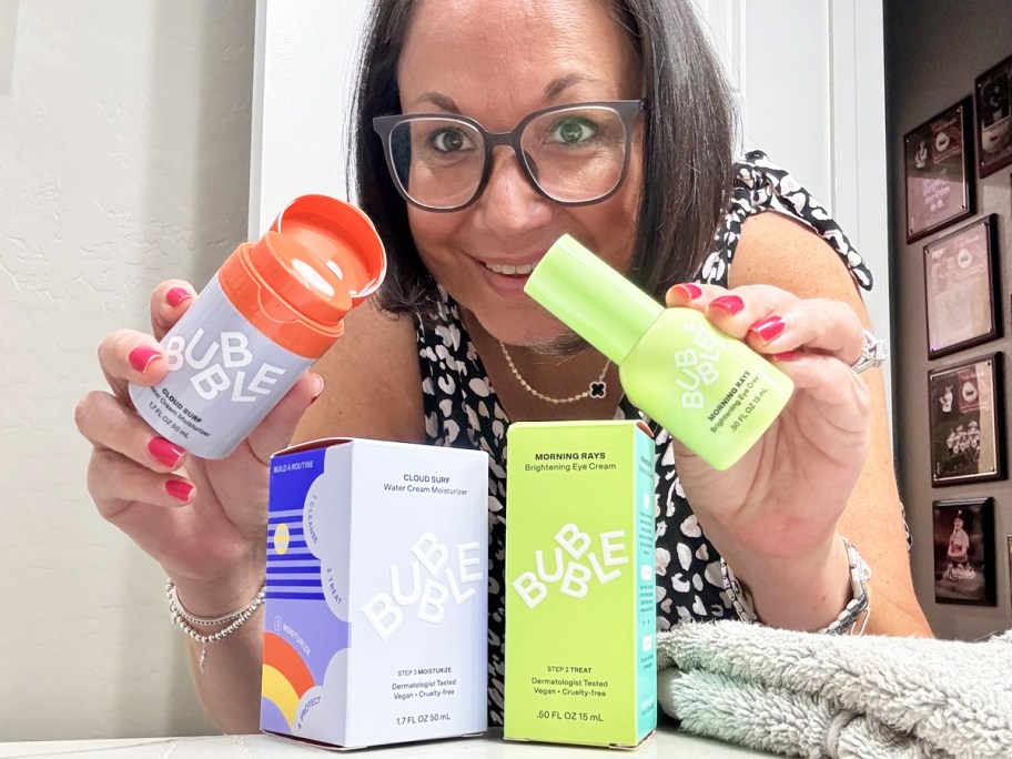 woman holding up two Bubble Skincare products in bathroom