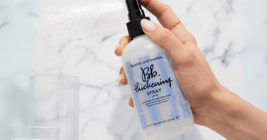 person holding bumble and bumble 8.5oz bottle of thickening spray