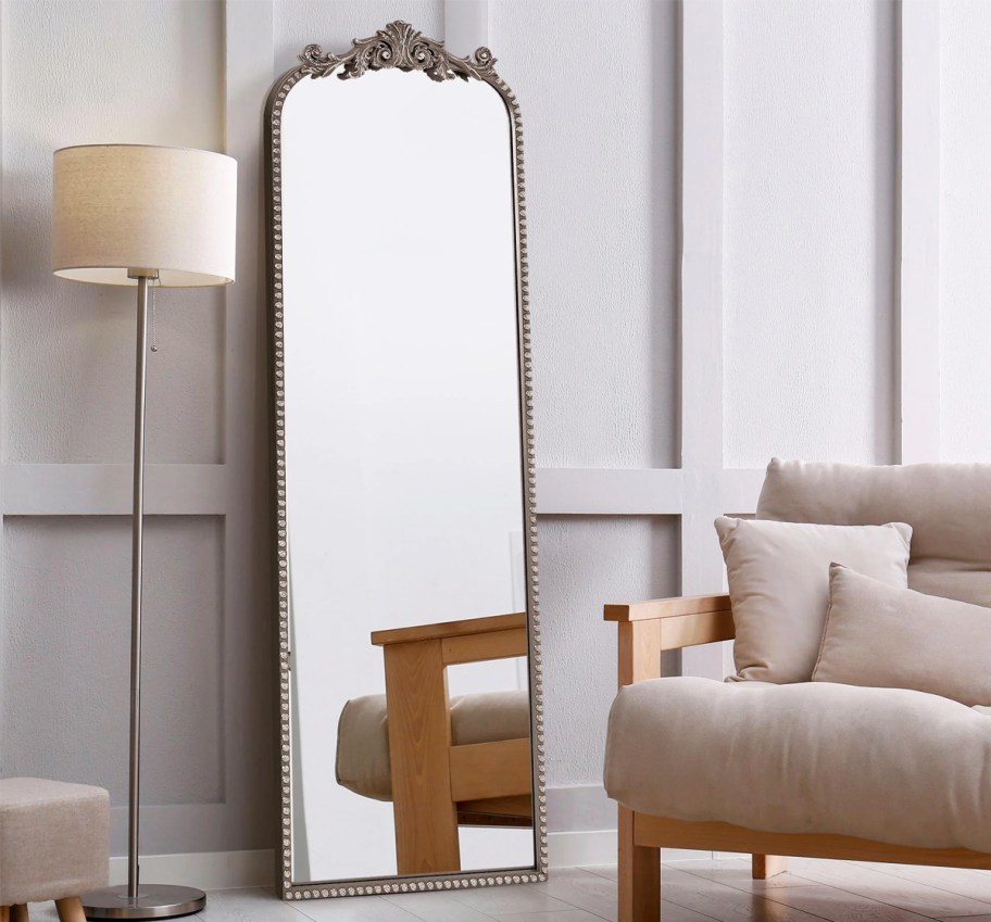 full length mirror with a black frame leaning against wall