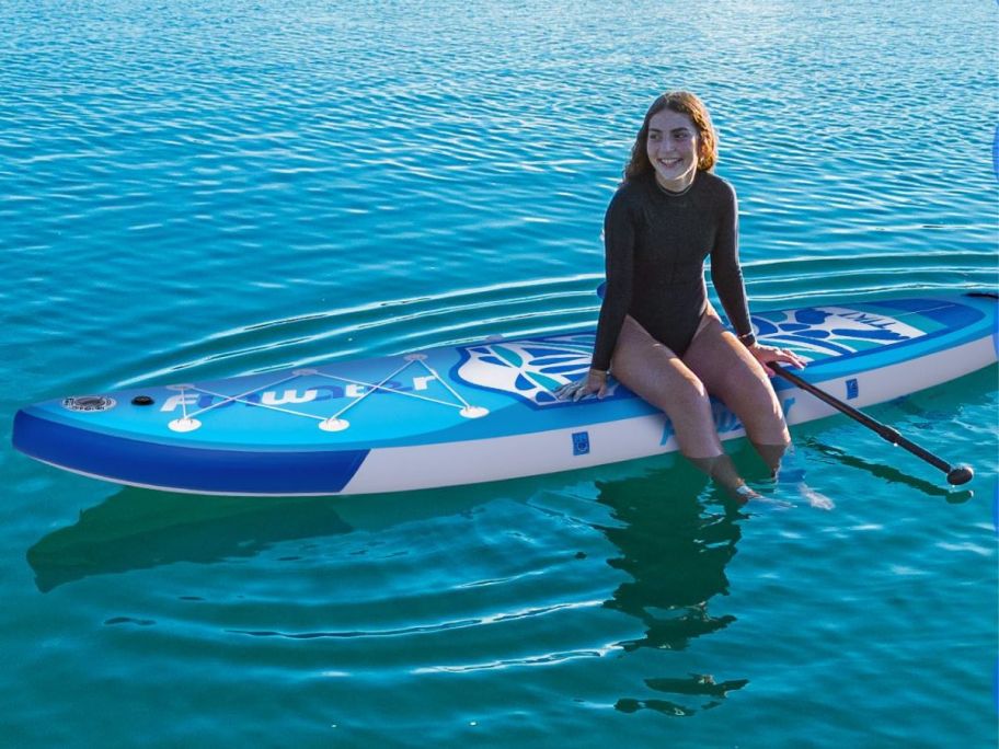 Tween girl sitting on a FunWater inflatable paddle board in water