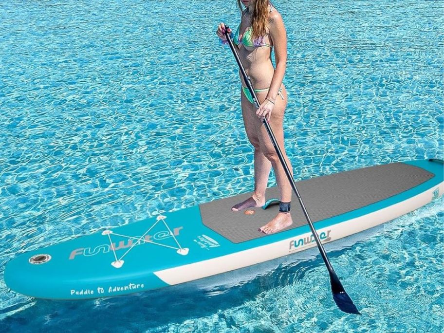 Woman standing on a FunWater Inflatable paddle Board in very clear blue water