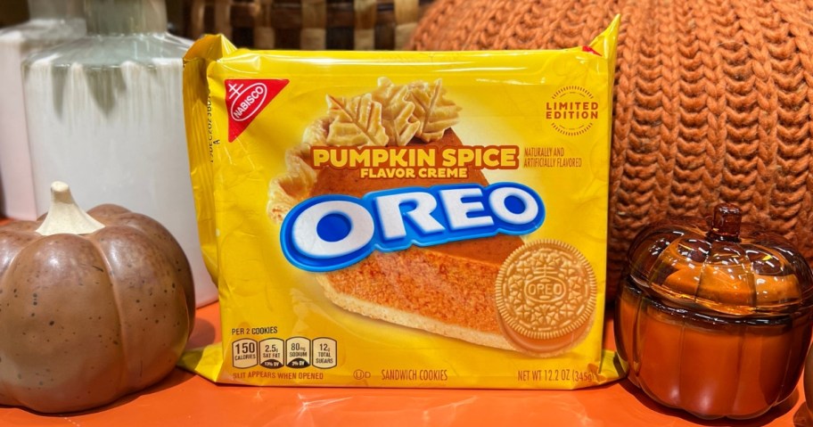 yellow package of Oreo pumpkin space cookies in between seasonal pumpkin decor and candles