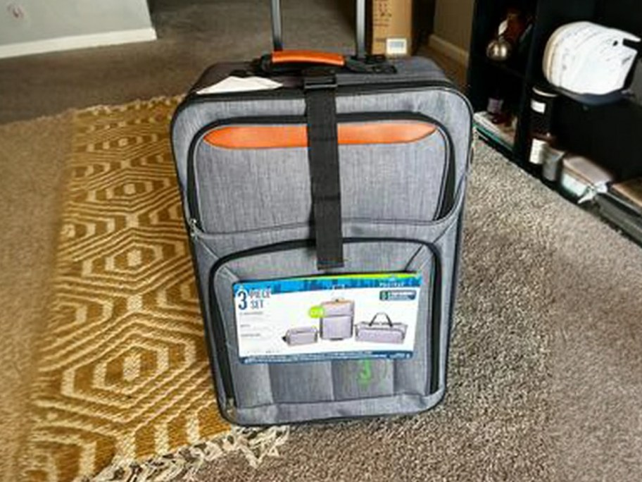 a light grey carry on luggage with handles in a living room