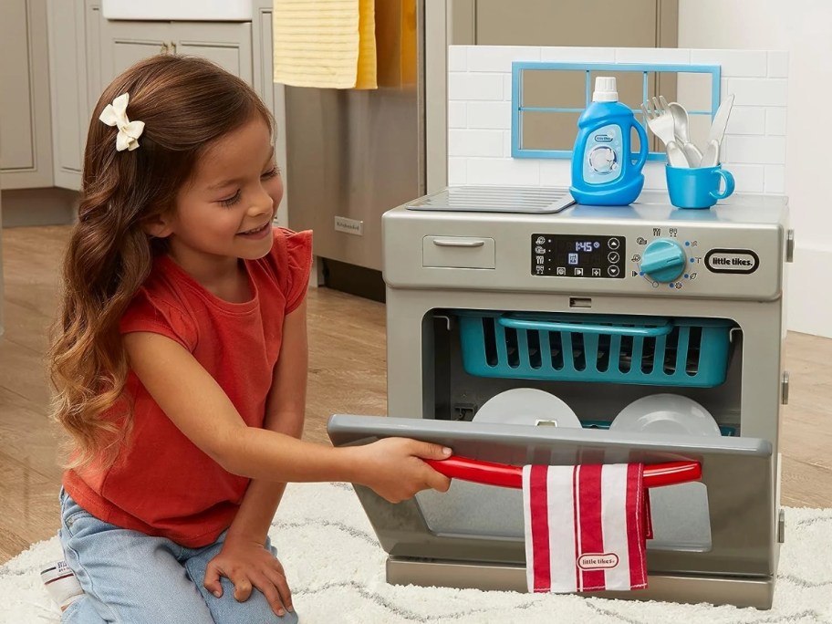 little girl playing with a toy dishwasher set