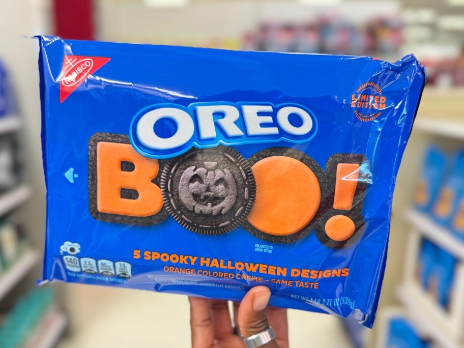 hand holding a blue package of OREO Boo! Halloween cookies with orange cream