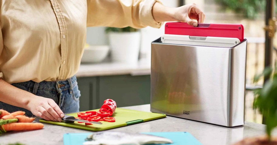 woman taking red cutting board out of holder on counter