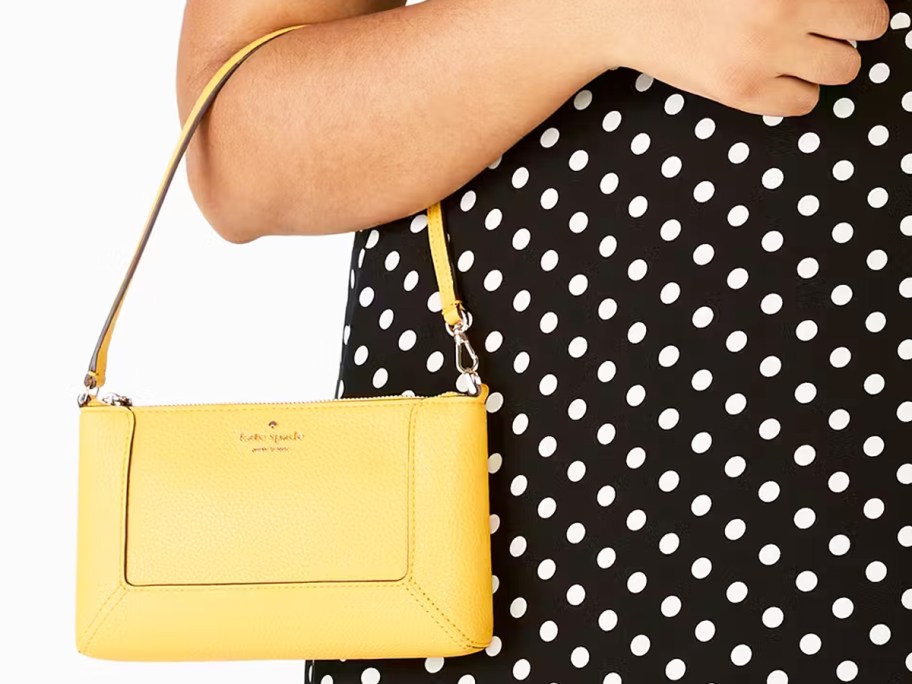 woman in a black & white polka dot dress with a yellow bag