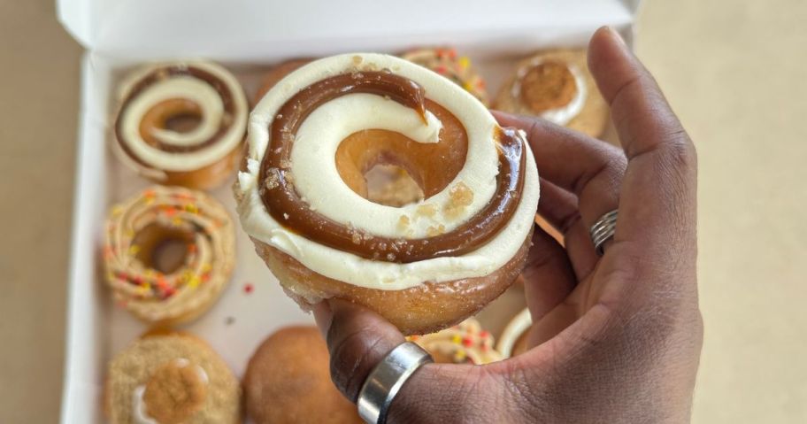 Hand holding a Salted Caramel Cheesecake Doughnut from Krispy Kreme