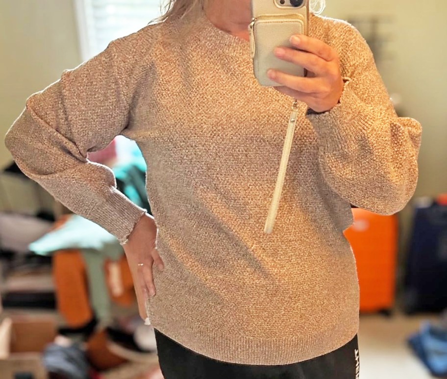 woman taking photo in mirror wearing a brown sweater