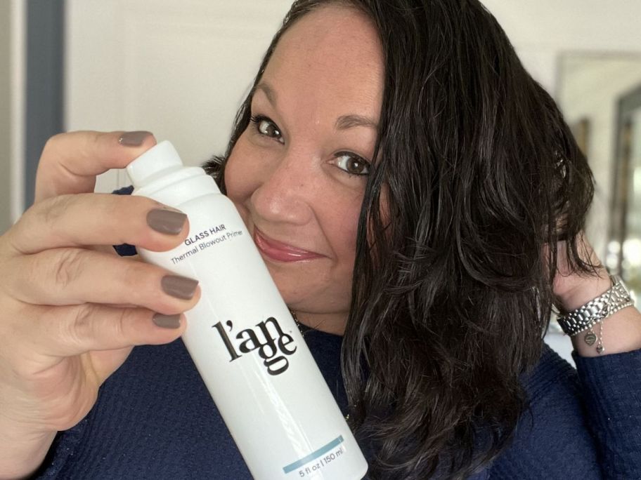 Woman holding a bottle of L'ange Glass Hair Primer