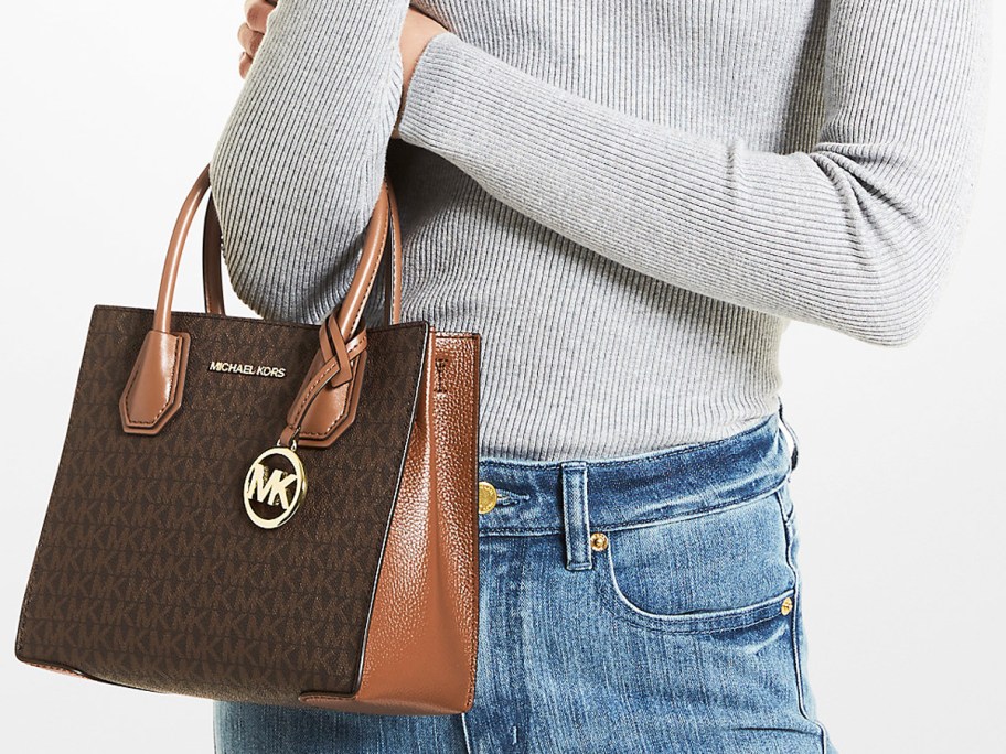 woman in grey top and jeans with brown purse