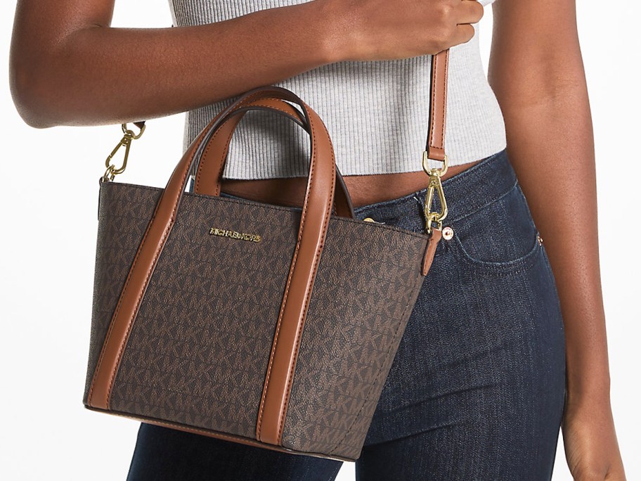 woman in a grey tank top and jeans with a brown purse