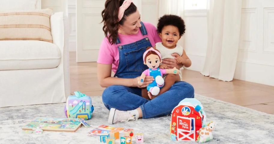 Ms. Rachel holding a baby while playing with Ms. Rachel Toys