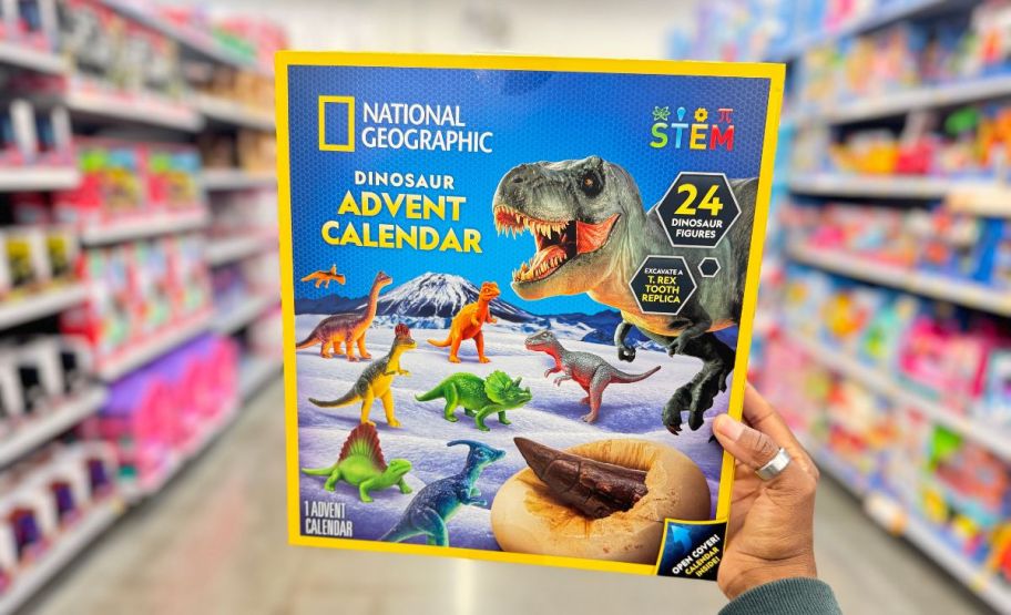 a womans hand shown holding a National Geographic Dinosaur Advent Calendar 