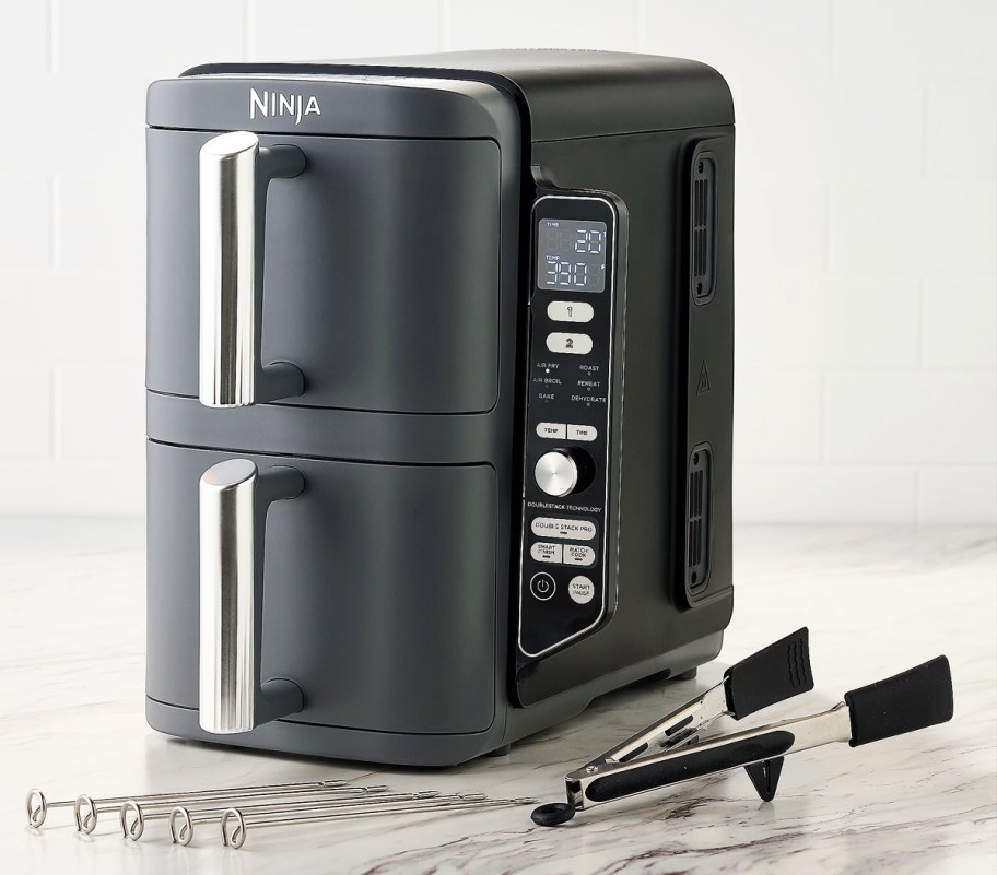 Ninja DoubleStack Air Fryer on counter with skewers and tongs