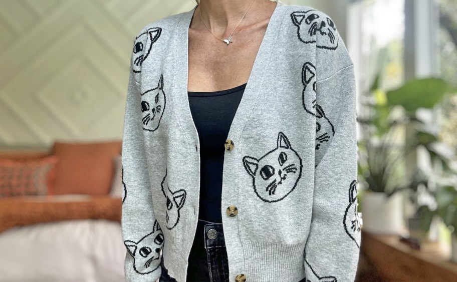 woman wearing a grey cardigan with black cat print