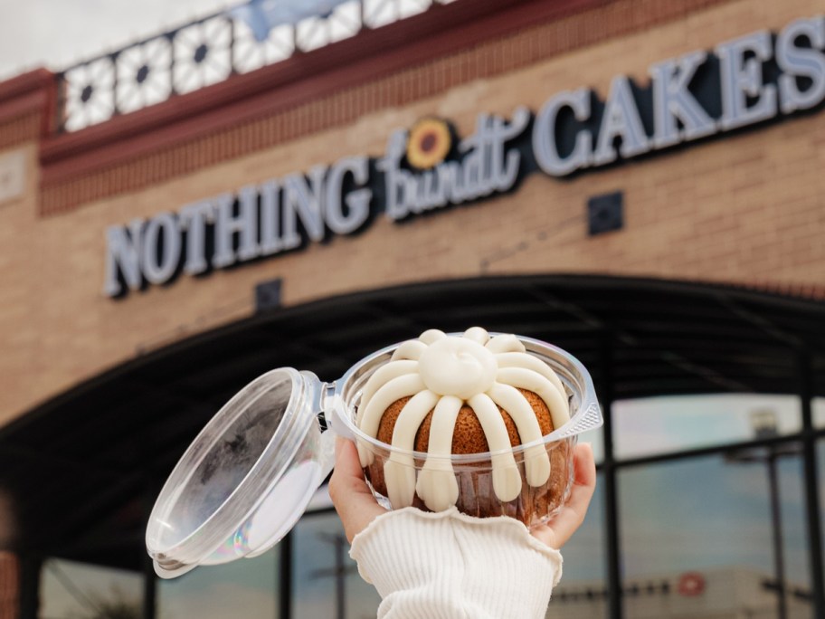 hand holding up a mini bundt cake outside of Nothing Bundt Cakes store