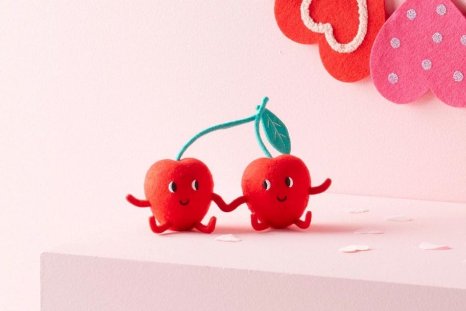 two felt cherry figurines on a mantle