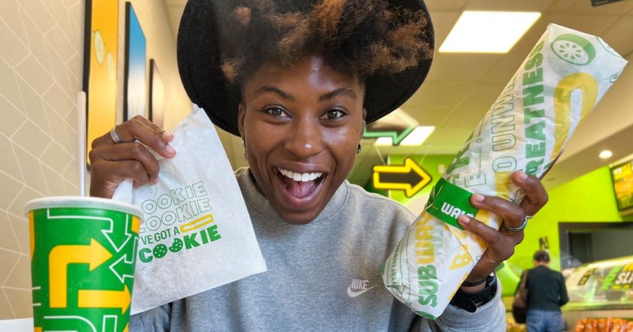 Woman holding a Subway Sub and a bag with a cookie