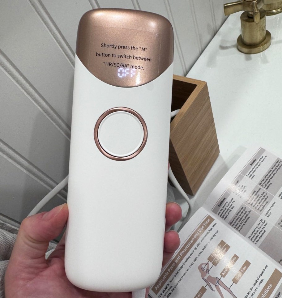 hand holding a white and rose gold ipl device