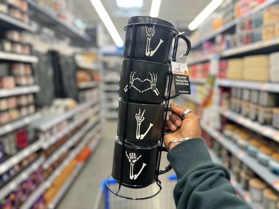 A person holding a stack of Black Skeleton Hand Stoneware Stackable Mugs