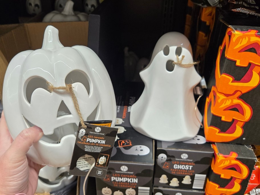 hand holding a white light up ceramic pumpkin, white light up ghost in the background