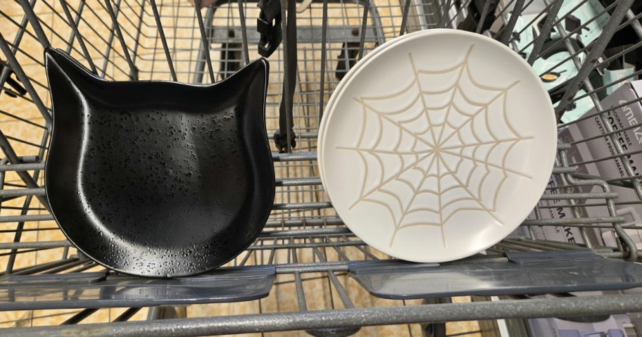 black cat shaped set of plates and white plates with spiderwebs in a shopping cart